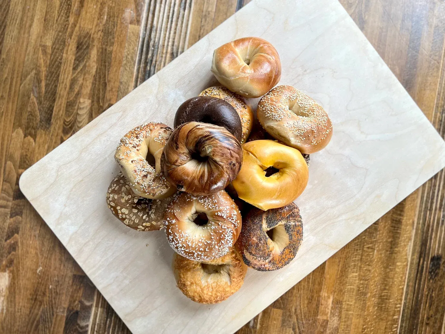 A dozen bagels arranged on a wooden board