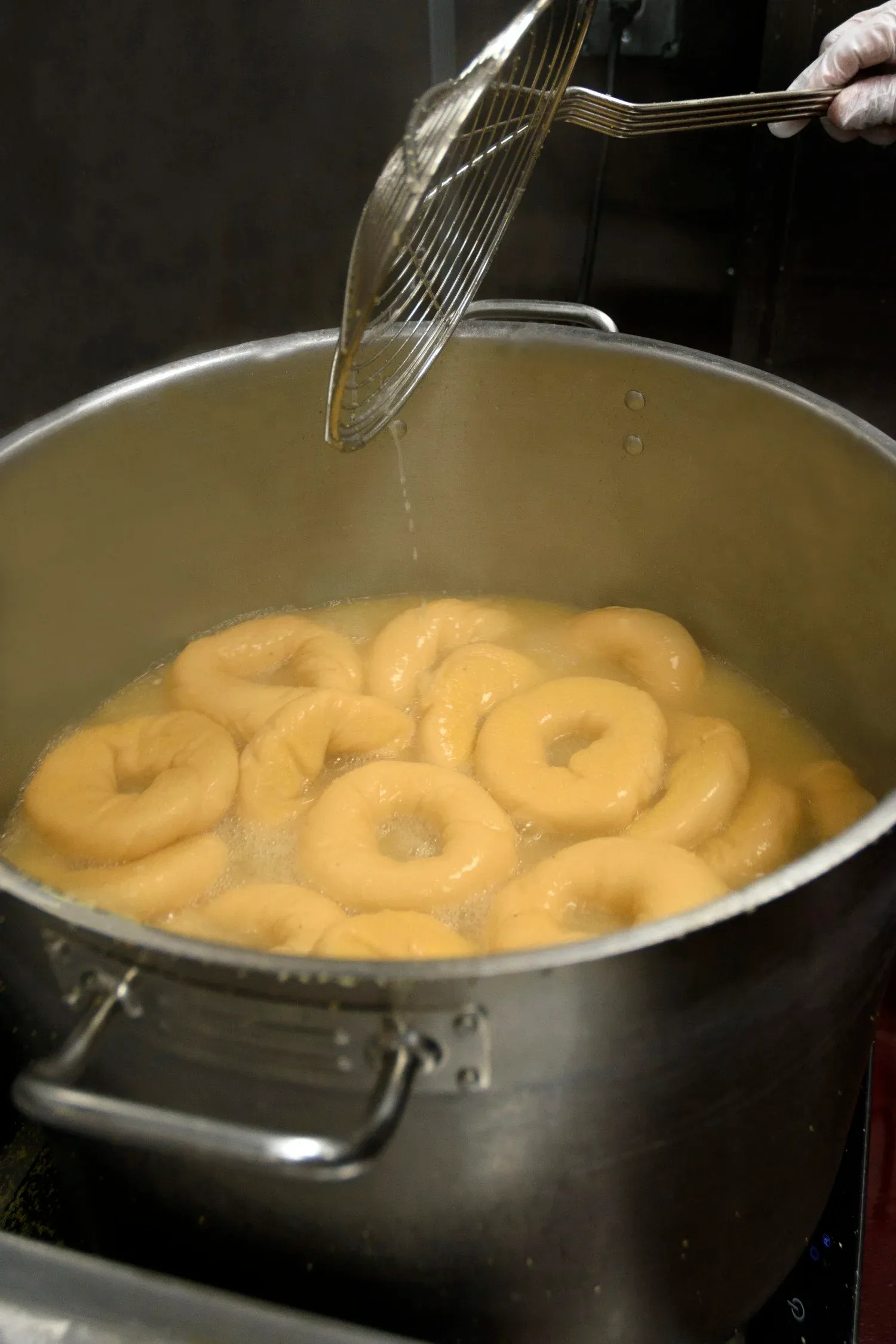Bagels boiling in a pot at Gotham Bagels