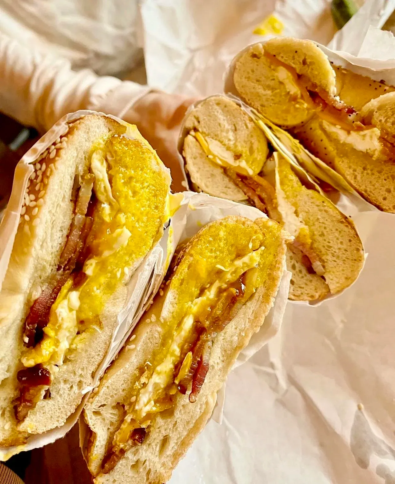 Two halved bacon egg and cheese bagel sandwiches