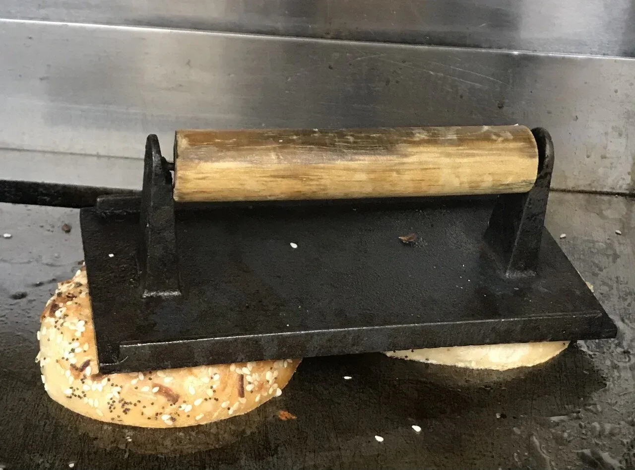 Sliced bagel on the griddle at Gotham Bagels