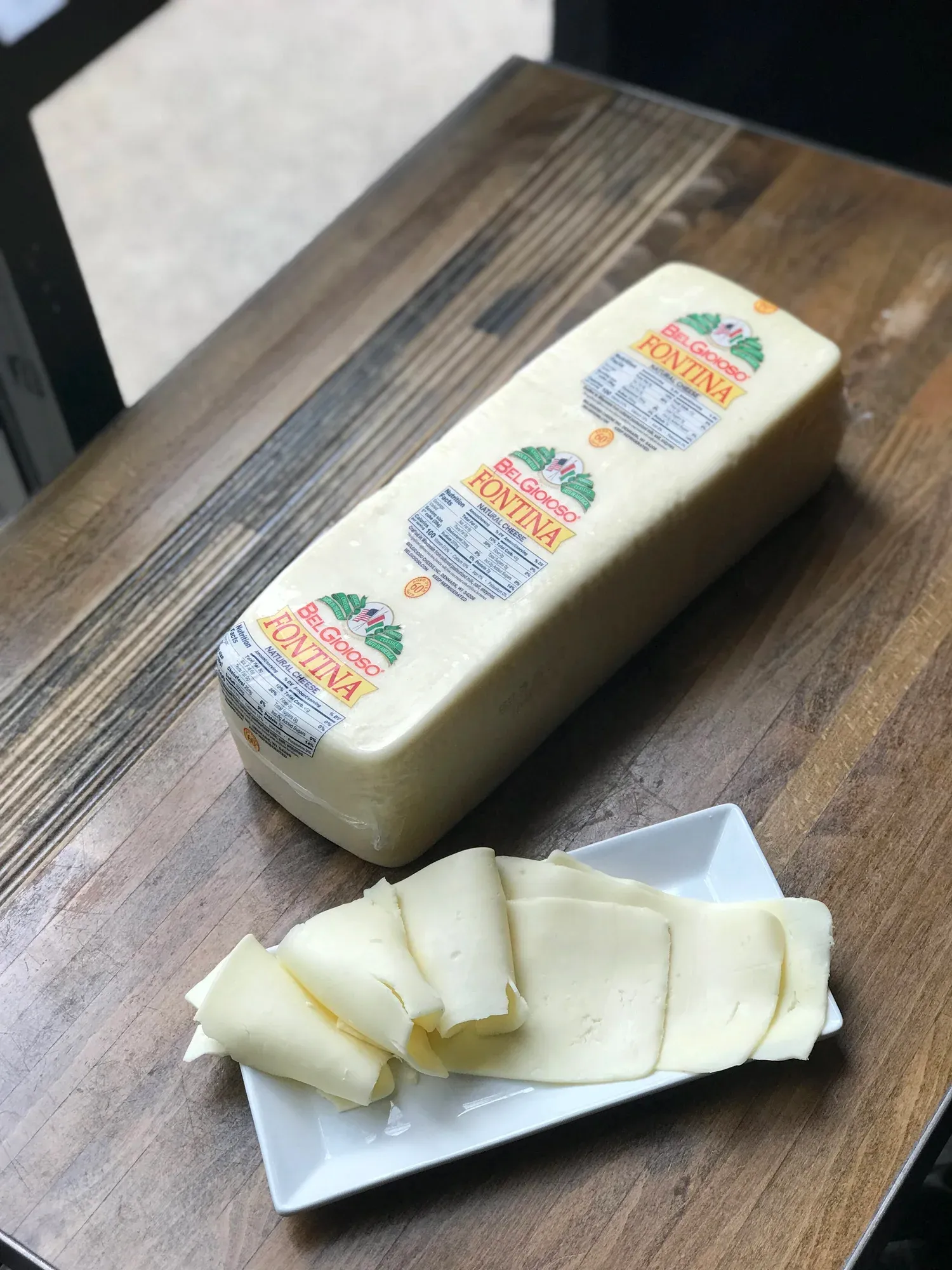 Sliced fontina cheese on a board