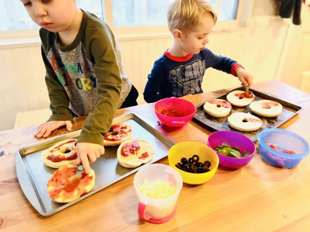 Young chefs making pizza bagels