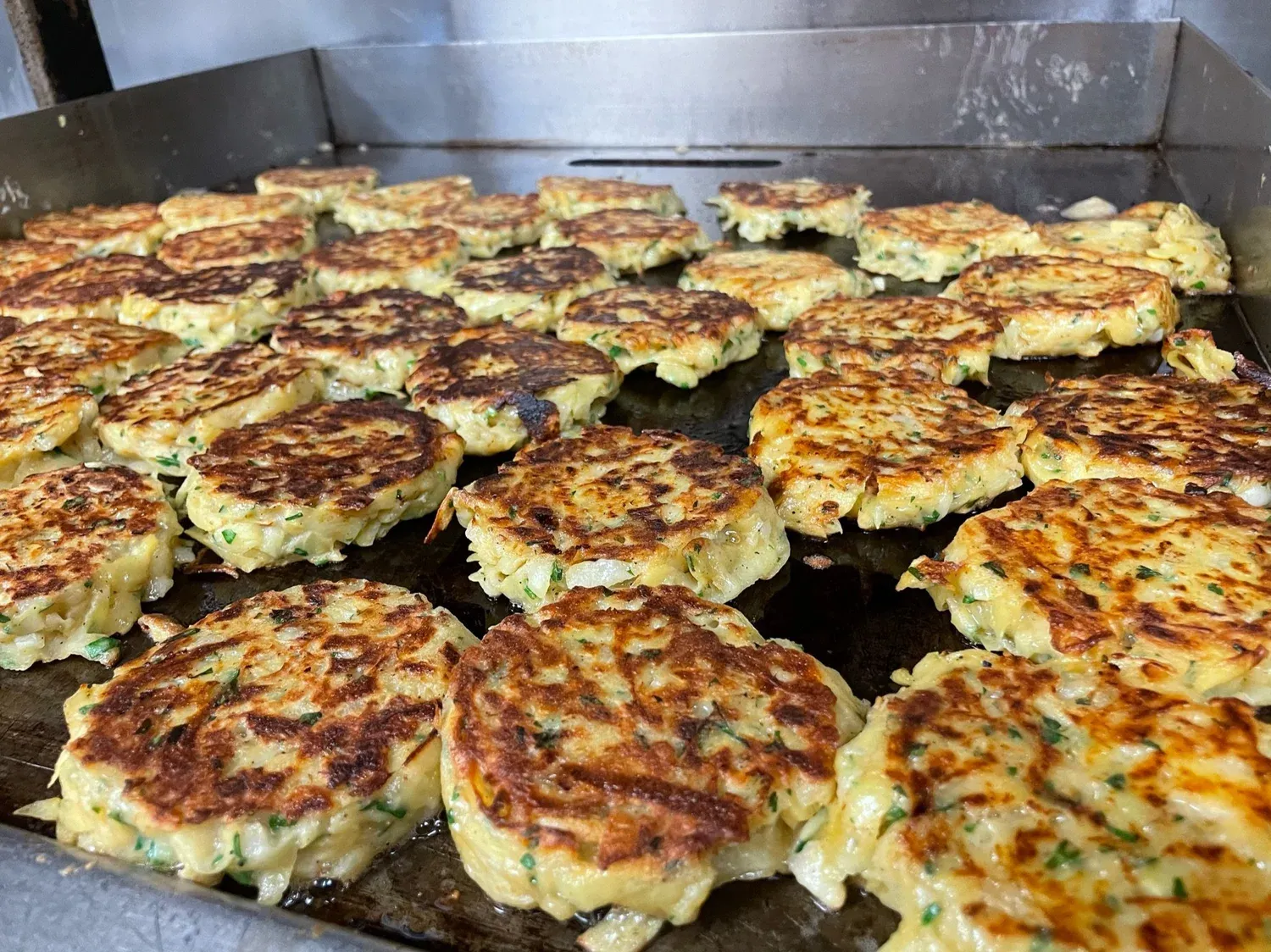 Potato latkes cooking on a griddle